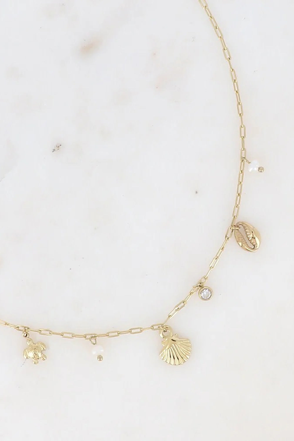 Collier doré pendentifs Gaïa - Bijou photographié sur fond en marbre blanc