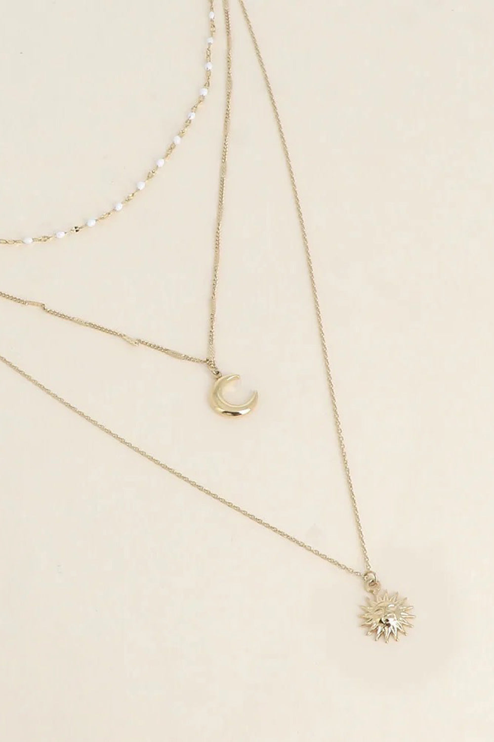 Collier triple doré Nova - Bijou photographié sur fond beige