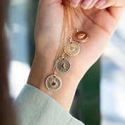Collier Mantra lune, soleil, étoile polaire, oeil protecteur laiton doré 3 microns imaginé et créé par Chloé Rose - Bijou photographié dans une main