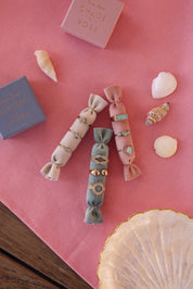 Bague dorée Cynthia goutte en aigue marine  - Bijou photographié sur coussins en velour rose posés sur une table en bois avec tissu rose,  boîte cadeau Chloé Rose et coquillages