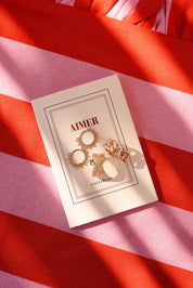 Bague dorée Marika grosse maille - Bijou photographié sur livre et tissu ligné rose et rouge