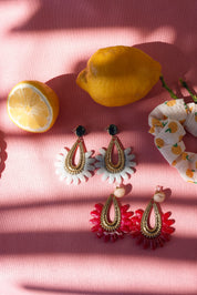 Boucles d'oreilles dorées Letizia bleu en acétate - Bijou photographié sur tissu rose avec citrons et élastique chouchou 