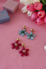Boucles d'oreilles pendantes dorées Marty vert en acétate - Bijou photographié sur tissu rose avec tulipes et boites cadeau Chloe Rose