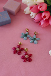 Boucles d'oreilles pendantes dorées Marty fuchsia en acétate - Bijou photographié sur tissu rose avec tulipes et boites cadeau Chloe Rose