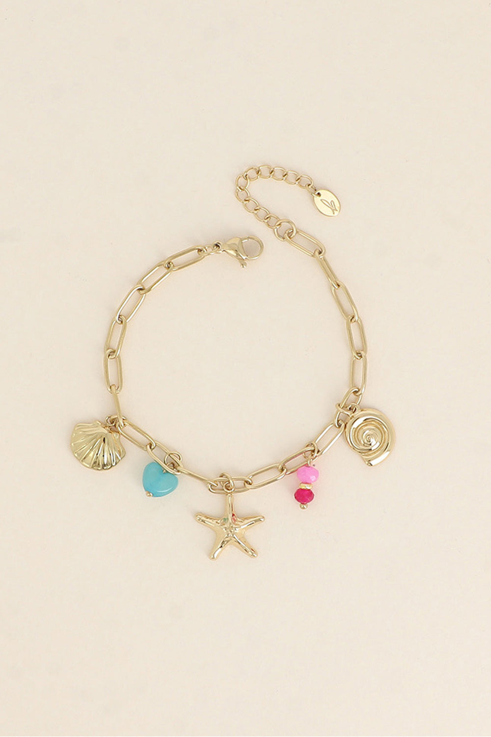 Bracelet doré Esmaa pendentifs marins et pierres naturelles - Bijou photographié sur fond beige