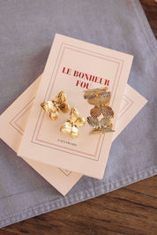 Bracelet manchette doré Palma papillon - bijou photographié sur livre "le bonheur fou" et tissu bleu