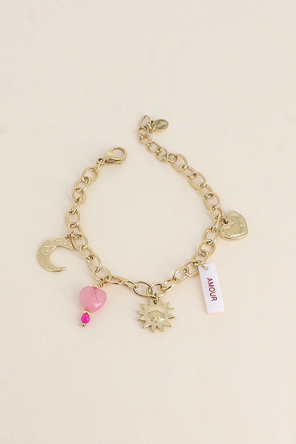 Bracelet maille doré Solal pendentifs soleil, cœur, Lune, pierres naturelles et amulette en nacre avec inscription "amour" - Bijou photographié sur fond beige