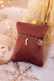 Bracelet doré Lorna en maille avec pendentifs lune, fleur, soleil, coeur et étoile - Bijou photographié sur un coussin rose en velours