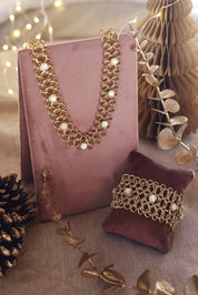 Bracelet manchette doré Dolli en maille épaisse orné de nacres - Bijou photographié sur un présentoir en velours rose foncé avec des décorations de Noël