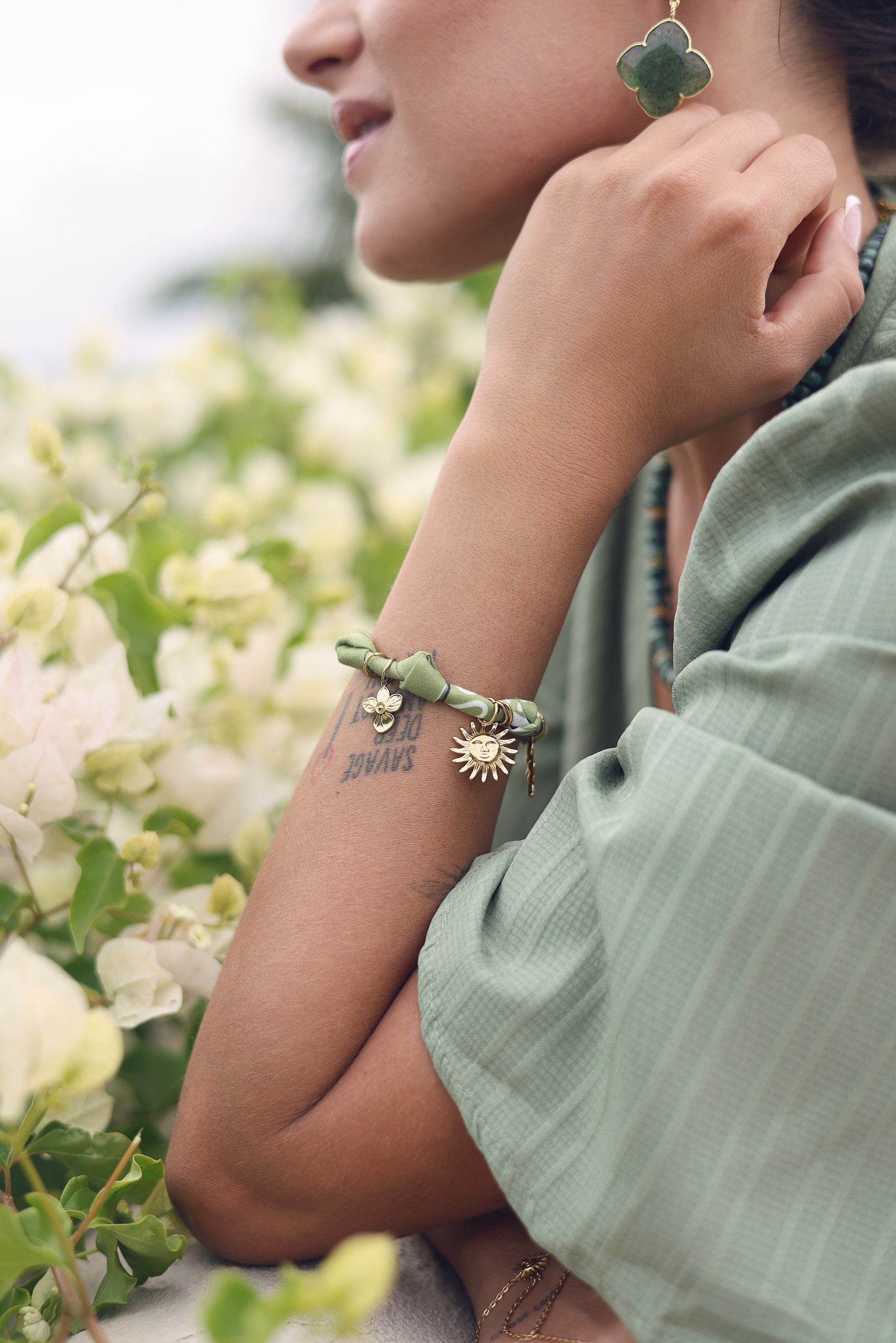 Bracelet doré Yarina bandana vert avec pendentifs soleil, trèfle, cœur, oiseau et fleur sertie d'un zircon - Bijou porté
