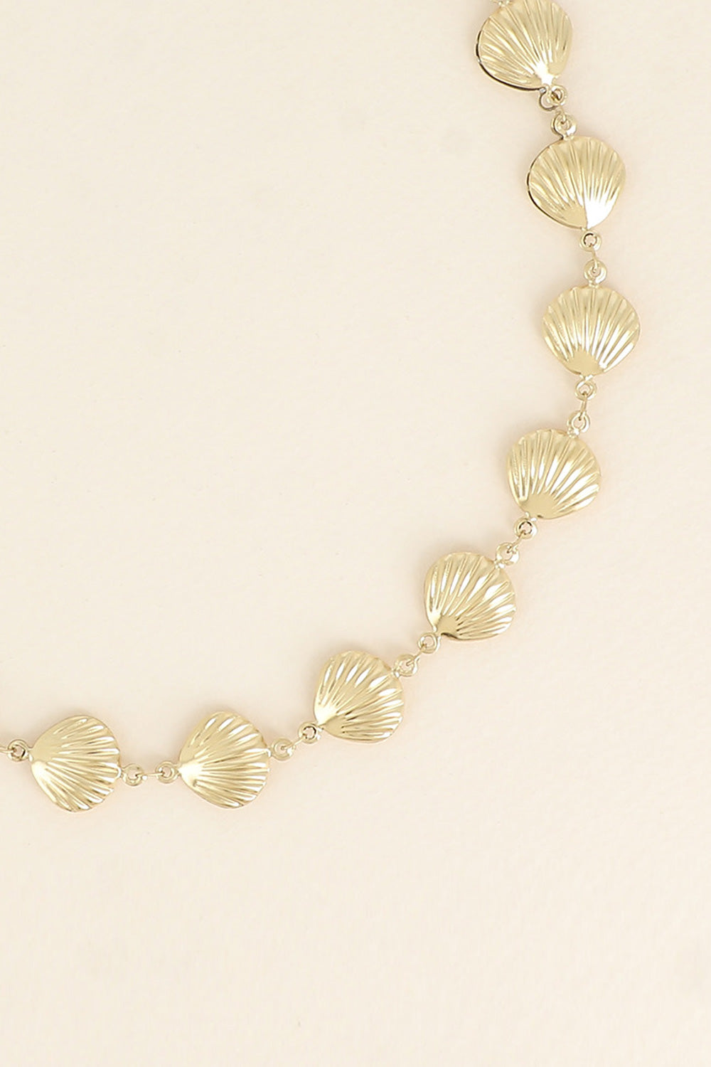 Collier doré Iva coquillages - Bijou photographié sur fond beige