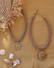 Collier doré Thao fleur gros cordon torsadé - Bijou photographié sur tissu jaune avec coquillages et paille