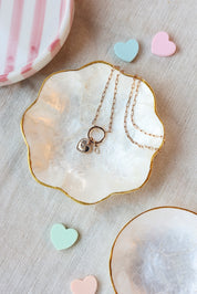 Collier doré Céline personnalisable en maille fine doté d’un anneau ouvrable pour accueillir initiales et charms - Bijou photographié dans une coupole en nacre avec des petits coeurs pastel