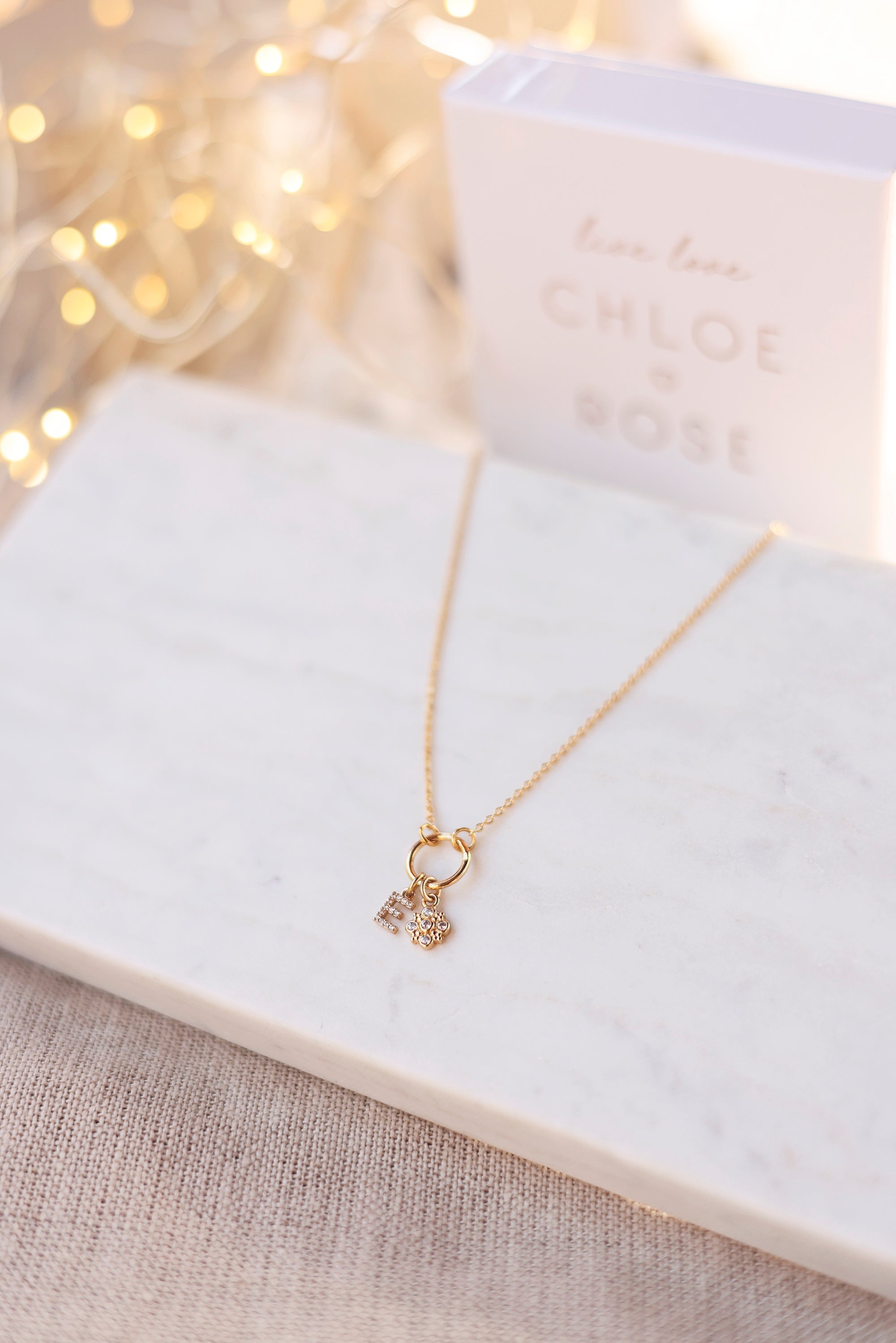 Collier personnalisable doré Delya anneau simple pour lettres de l'alphabet et charms - Bijou photographié sur un présentoir rectangulaire en marbre blanc